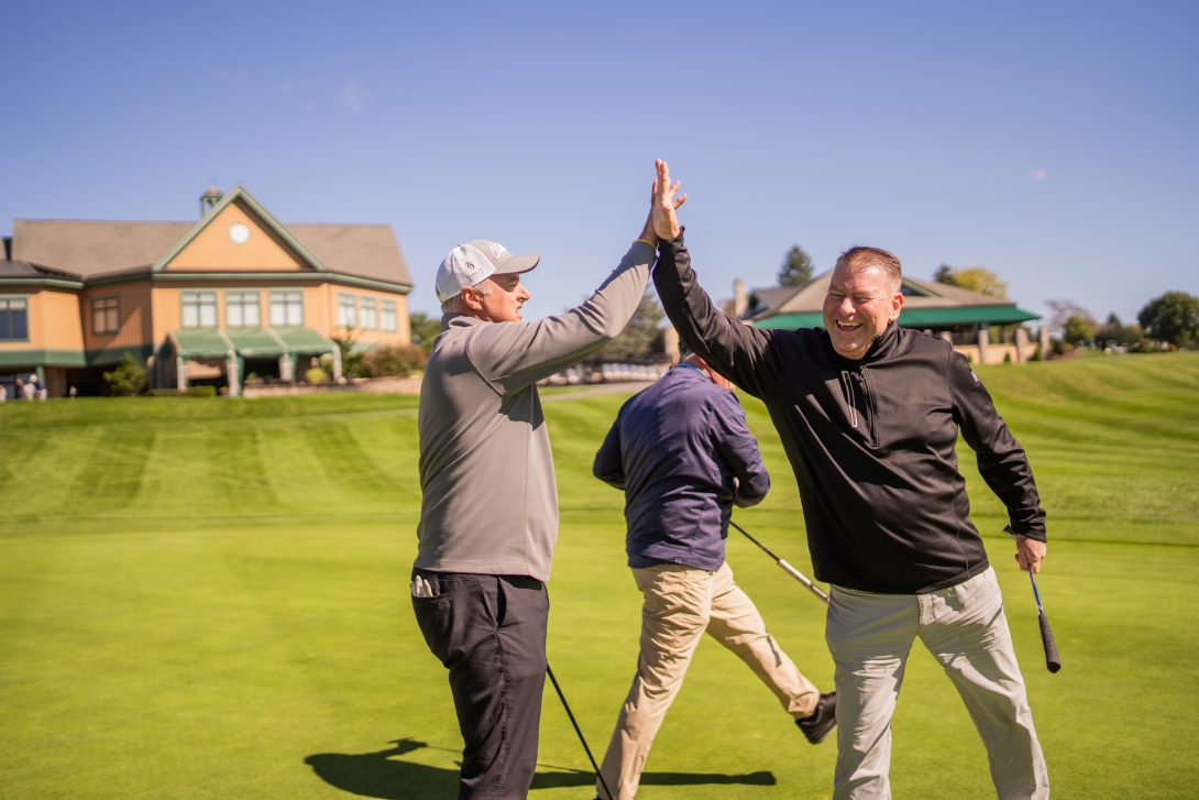 Golfers celebrate a made putt at the MITER Foundation charity golf outing in Hershey.